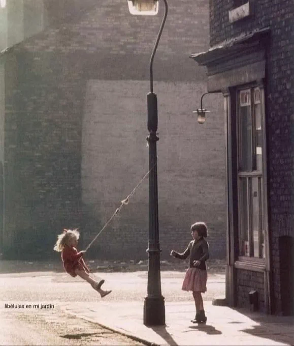 Dos niñas se balancean en una farola, Mánchester, 1965 © Shirley Baker