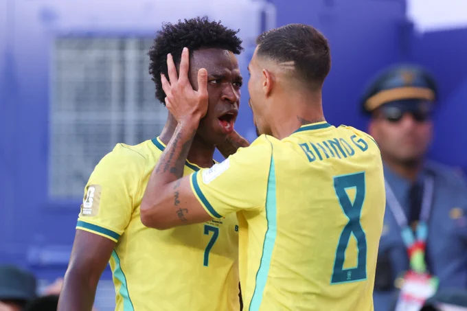Two men in yellow soccer jerseys, one with his hands up, appear to be having an animated conversation on a soccer field.