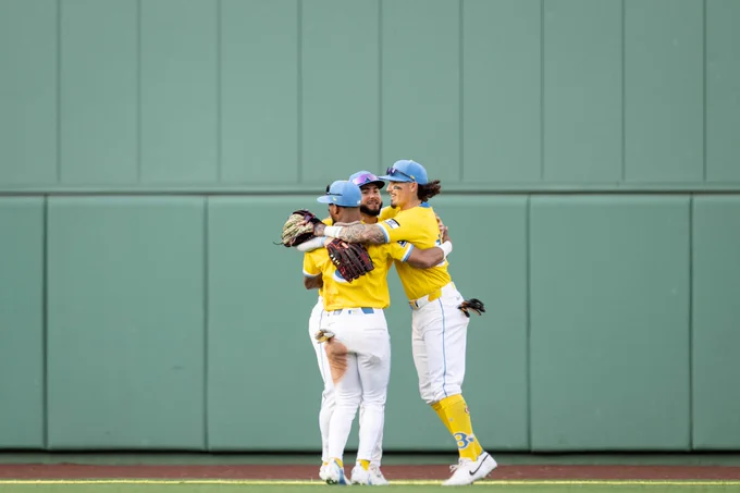 Jarren Duran, Wilyer Abreu, Ceddanne Rafaela in the outfield hugging each other wearing their city connect yellow and blue celebrating the win. 