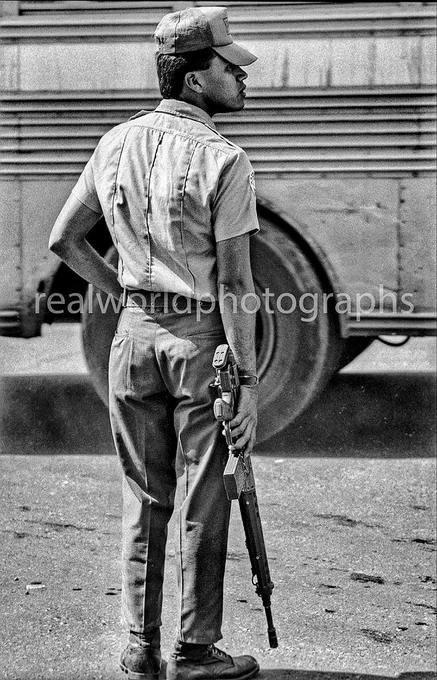 A Salvadoran police officer patrols a San Salvador street. El Salvador, CA. 1993. Gary Moore photo. Real World Photographs. #ElSalvador #photojournalism #nineties #Grok #Nikon  #streetphotography #police  #realworldphotographs #garymoorephotography #crime #images #stock