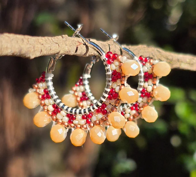 silver tone hoop earrings with beads in shades of cream, gold, and brown, with the brown glowing reddish in the sunlight