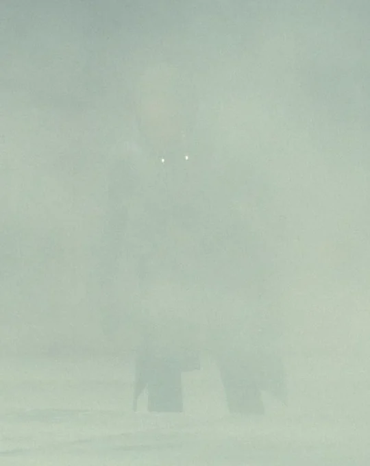 thunderbolts* screenshot. ava emerging from a cloud of dust after helping to push over the concrete slab. there is white dust everywhere but the very bright white lights on her suit’s collar are visible through it