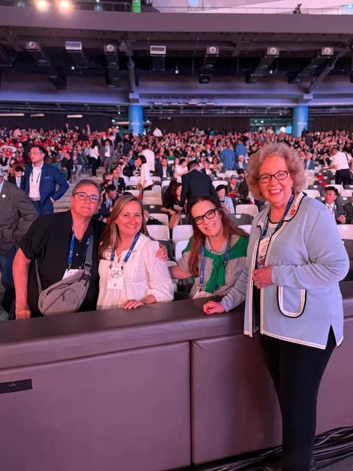 Four Rotary members pose near the front of a crowded convention venue ahead of a general session