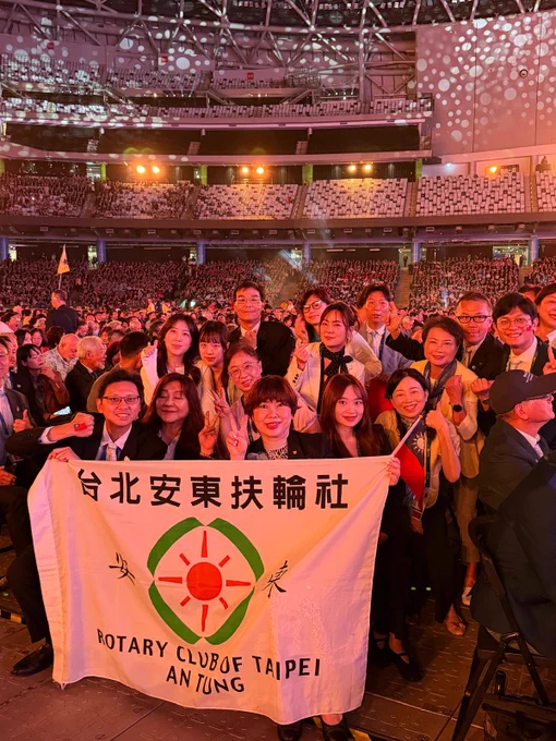 Members of the Rotary Club of Taipei Antung pose with their club banner on the convention floor surrounded by fellow attendees.
