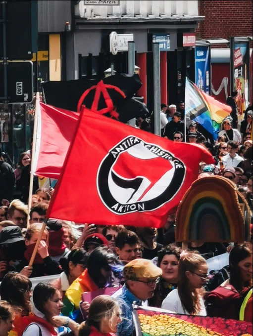 Der Demozug nähert sich dem Berliner Platz, viele Menschen, vorn Antifa-Fahne, hinten Pride-Fahne