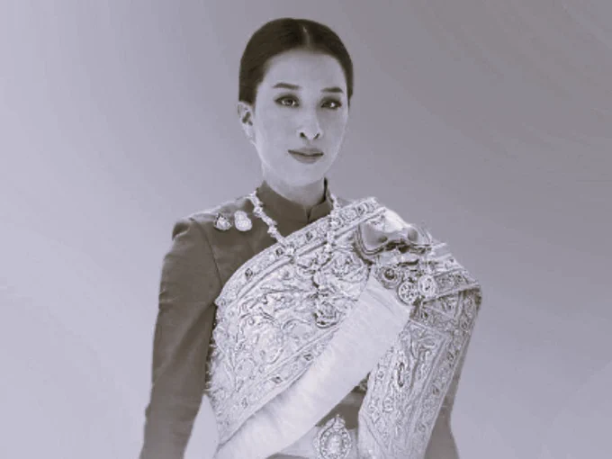 A woman dressed in a traditional outfit adorned with intricate embroidery and decorative elements. She stands confidently, although her face is obscured, adding a sense of mystery to her presence.