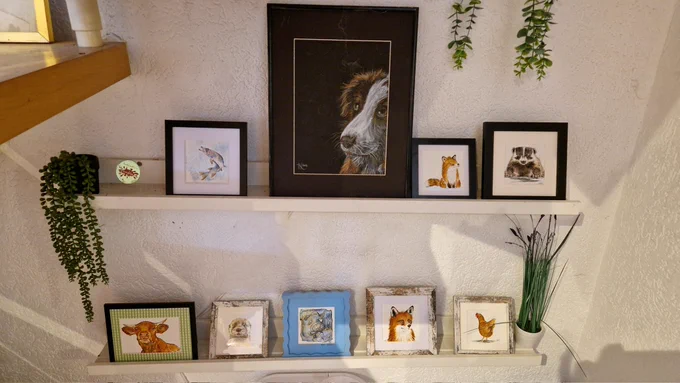 Auf zwei Borden aufgereiht sind 9 handgemalte Bilder, eins davon ein unverkäufliches Portrait meiner Hundedame , sowie kleinere quadratische Bilder mit dem Motiv Dachs, Hecht, Huhn, 2x Fuchs , ein kleines blaues abstraktes Bild und ein mittelgroßes rechteckiges Bild Motiv Kuh 