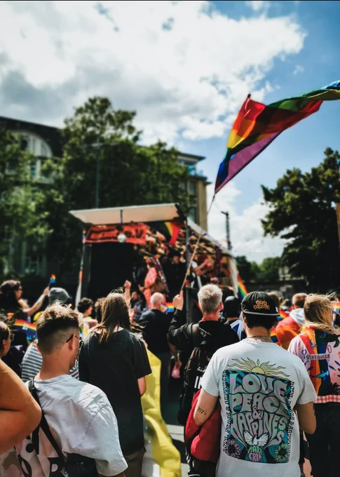 Der Demozug auf der Feilenstraße, viele Menschen, eine bunte Fahne, ein T-Shirt sagt: "Love, Peace & Happiness"