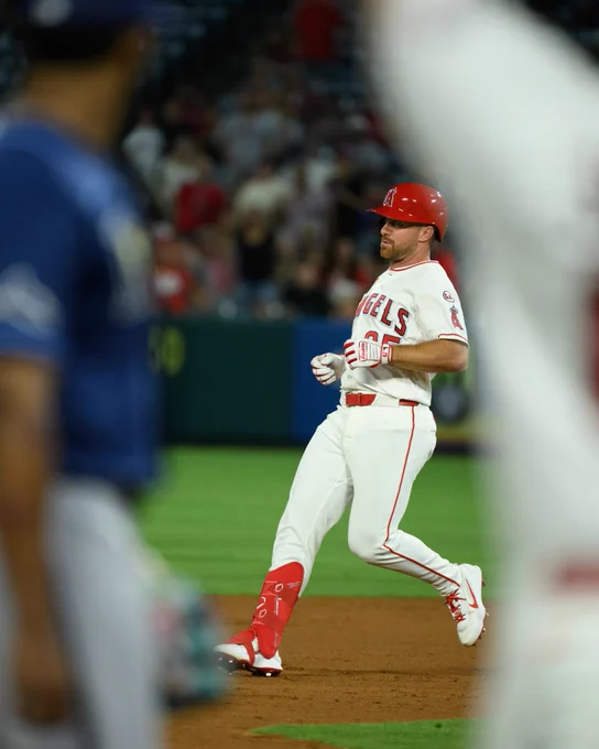 Donovan Walton, framed by the Rays third baseman and the Angels Third Base Coach who are both blurred in the foreground, jogs to second base after hitting a double. 