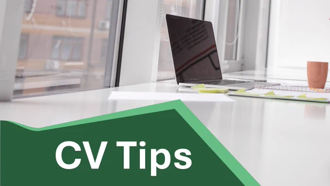 Bright, modern workspace by a large window with a laptop on a white desk, alongside a spiral notebook, sticky notes, and an orange mug. In the foreground, a green graphic banner overlays the image with the text “CV Tips” in bold white letters.