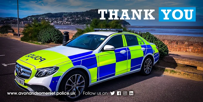 A police car with blue and lime green markings parked by the sea, with "THANK YOU" text above.