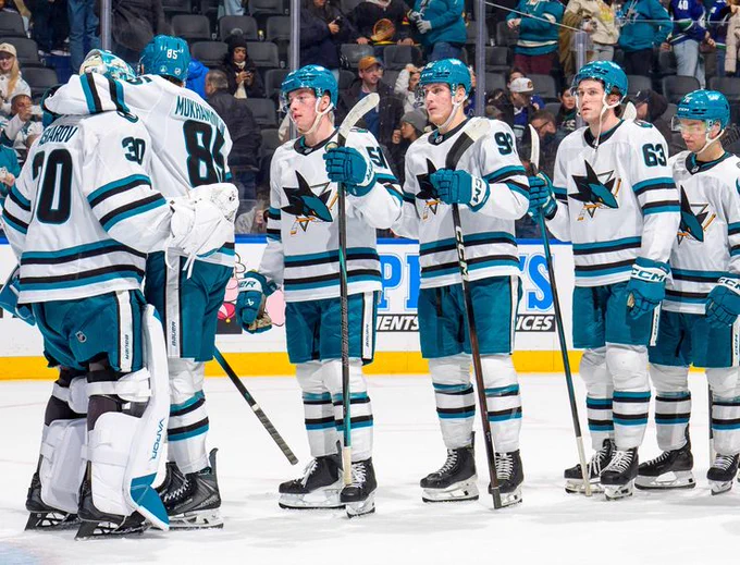 Sharks players (Shakir Mukhamadullin, Collin Graf, Igor Chernyshov, Zack Ostapchuk, and William Eklund) in line to congratulate Yaroslav Askarov after a win in white away-jerseys