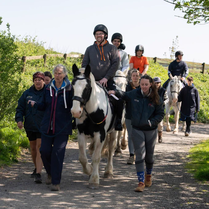 Photo showing a group of people smiling whilst horse riding on a Back Up multi-activity course.