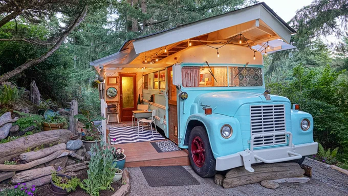 A 1969 International school bus converted into a retro tiny house, lit up at night