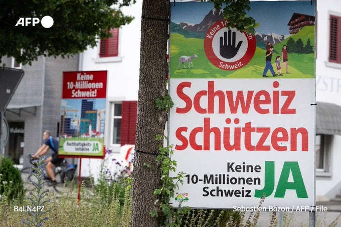 File photo shows a cyclist riding past campaign posters ahead of an anti-immigration initiative launched by the Swiss People's Party (SVP) and reading "No to a Switzerland of 10 million - Sustainability YES" and "Protect Swizterland, no to a Switzerland of 10 million - YES", in Thayngen, northern Switzerland, on June 1, 2026