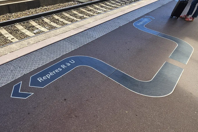 Marquage au sol indiquant la direction à prendre sur le quai en fonction  du repère indiqué dans la composition du train. Ici sur la flèche de gauche repères R à U et sur la flèche de droite repères V à Z (photo perso, Lyon Part Dieu 14/06/2026)