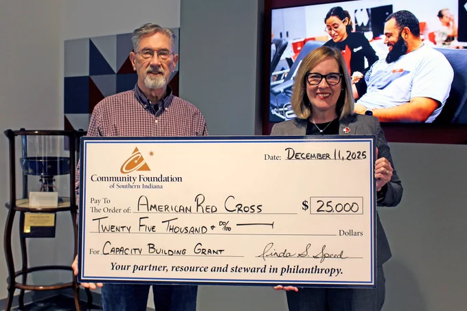 Two people hold a check for $25,000 meant for the American Red Cross. the check is from the Community Foundation of Southern Indiana.