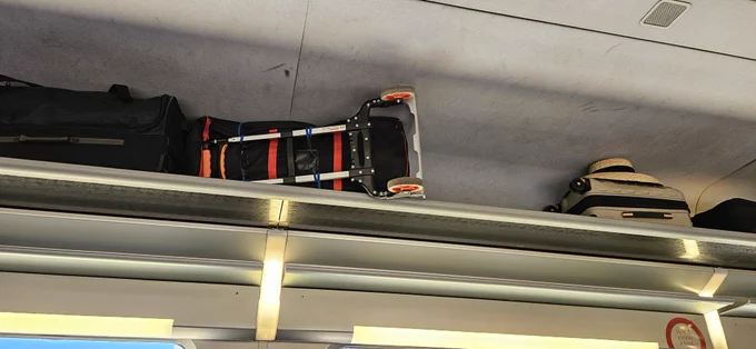 Bagage fixé sur un chariot à l'aide de tendeurs rentré de force dans le compartiment bagage au dessus d'un siège (photo perso, 14/06/2026)