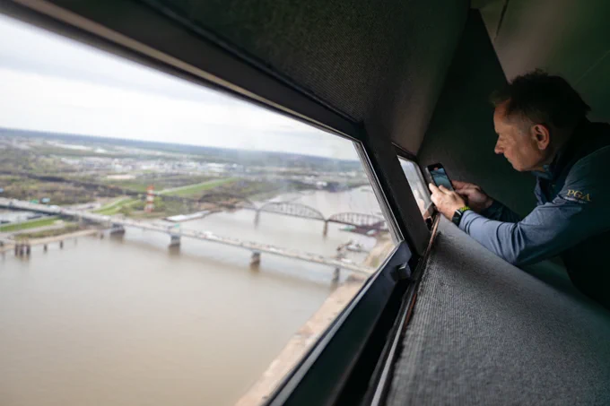 Man taking a photo from the view at the top of the Gateway Arch looking over the Mississippi River.