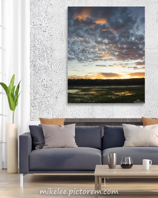 A vertical composition from atop a rock outcrop at Kyburz Flat in Sierra County, California, takes in both the marsh below and the full height of the sunset sky above. The gap along the horizon where the cloud layer breaks allows sunlight to push vertically upward into the frame, a warm column of light rising into the darker cloud mass overhead. Marsh grasses and open water occupy the lower portion of the image, the elevated position showing more of the wetland than the shoreline allowed. The vertical framing was a decision the sky made, not the photographer. June, Sierra County.