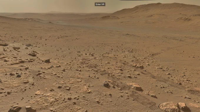 An ochre-toned image capturing a Martian landscape, with the tracks of the rover receding in the distance. A button offers to Enter VR.