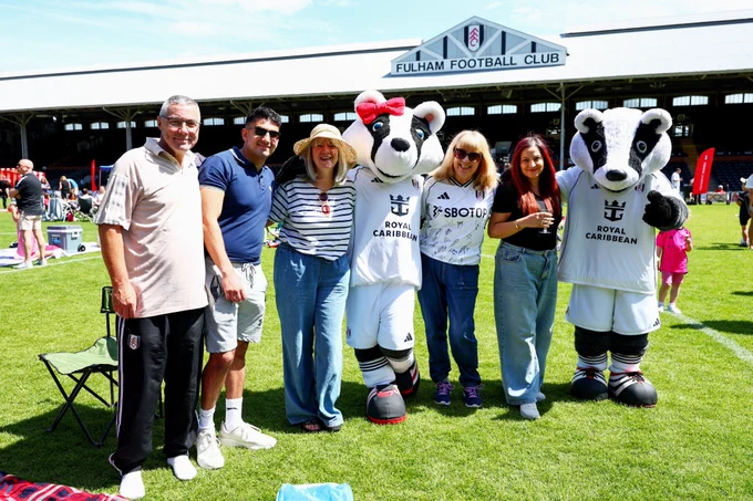 A group of Fulham fans pose for a picture with Billy and Bella the Badger in front of the Johnny Haynes Stand.