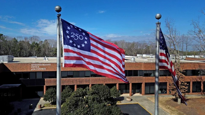 Exterior view of the North Carolina Judicial Branch building in Raleigh, North Carolina, with the Betsy Ross 250 Flag and the United States Flag flying side by side in the wind. Photo credit: North Carolina Judicial Branch.