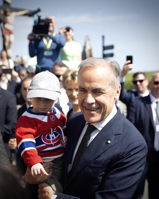 Prime Minister Carney holds an infant wearing Montréal Canadiens jersey in County Mayo, Ireland.