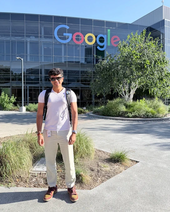 Smit wearing a white t-shirt standing smiling in front of the Google Mountain View office. 