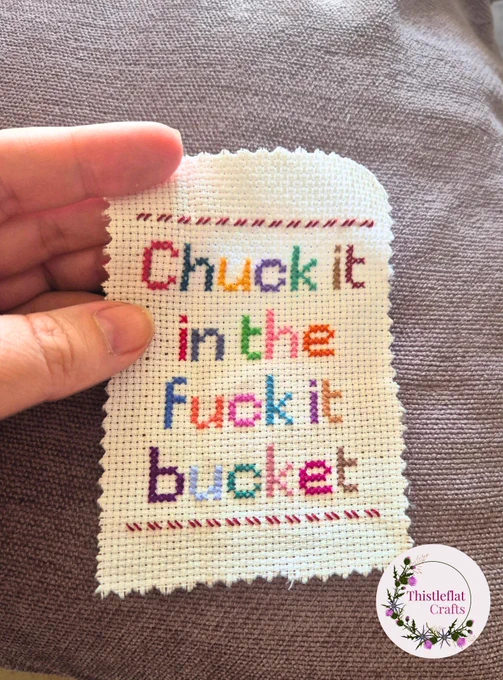 Mini cross stitch wip in multiple colourful threads saying 'Chuck it in the fuck it bucket'