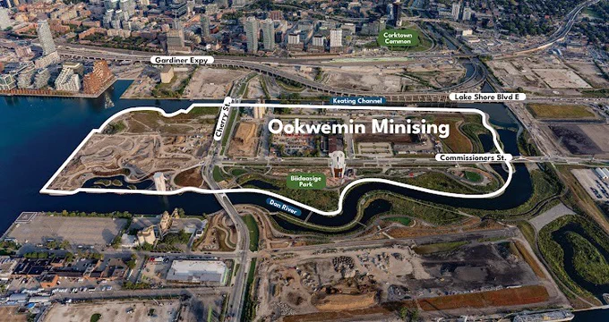 Aerial view of a construction site labeled "Ookwemin Minising" with outlined boundaries. Nearby are iconic roads including Gardiner Expressway, Lake Shore Boulevard East, and Commissioners Street. Adjacent to the site is the Keating Channel and Don River, with surrounding urban and water areas. Prominent green space labeled "Corktown Common" is visible in the top area.