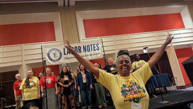 Elise Bryant of the DC Labor Chorus stands in front of a combined supergroup of singers during a special performance at the Labor Notes Fundraising Dinner.