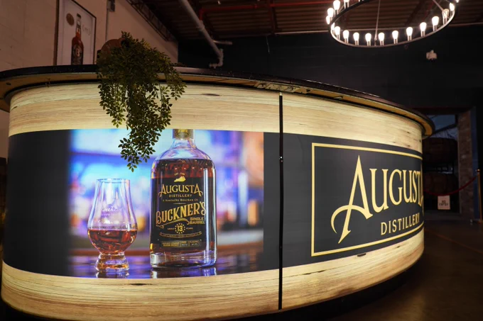 Close-up of a bottle of Buckner's whiskey on a wooden bar counter at Augusta Distillery