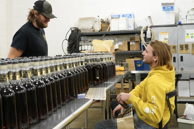 Two Augusta team members talking while packaging bourbon bottles