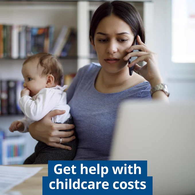A person is sitting indoors, holding a baby, and speaking on a smartphone. In the background, there is a bookshelf. The text on the image reads, "Get help with childcare costs."