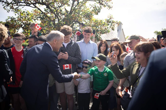 Le premier ministre Mark Carney rencontre des membres de la communauté d’Aughagower dans le comté de Mayo, en Irlande. Il serre la main d’un enfant vêtu d’un chandail de l’équipe de soccer irlandaise.