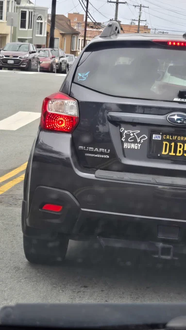 Black Subaru with a car sticker featuring Pikachu saying "hungy"