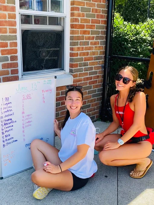 Female staff member and female lifeguard working on the whiteboard at the Parma Heights Community Pool opening.