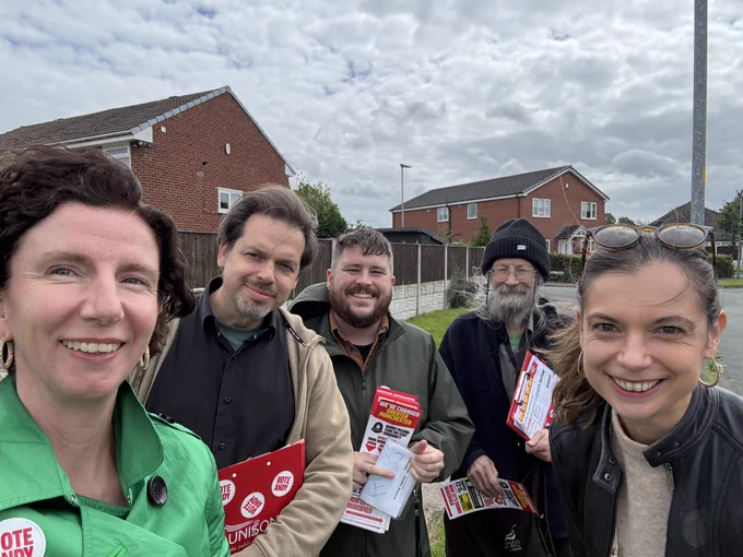 Anneliese stood taking a selfie with campaigners with some holding leaflets, and houses in the background.