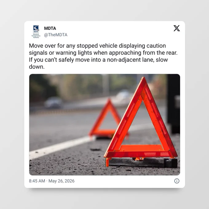 Close-up of two red reflective emergency triangles placed on the roadside to warn approaching vehicles of a stopped vehicle ahead.