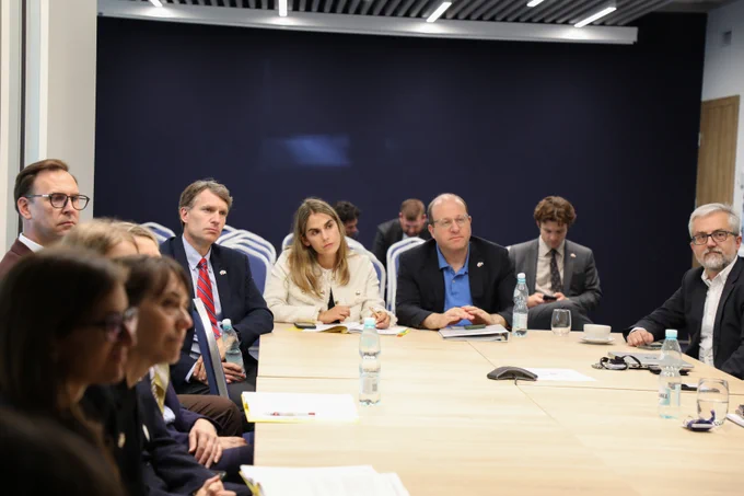 Group of professionals seated around a conference table engaged in a business meeting in a modern office room.