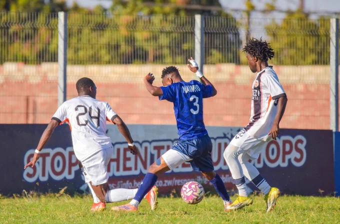 Three soccer players in an intense game moment, highlighting competition and athleticism, with colorful uniforms and a grassy field.